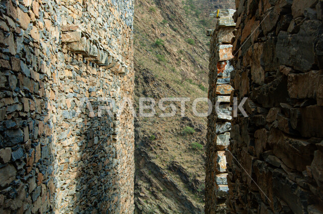 Ancient Arab architecture, rocky terrain, mountain peaks and heights, heritage stone buildings and houses, the ancient village of Dhi Ain in the city of Al Baha in the south of the Kingdom of Saudi Arabia, famous historical tourist attractions, natural places to attract and attract tourists