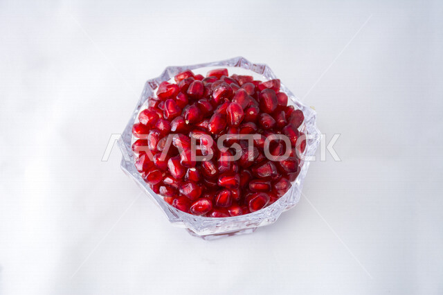 صورة مقربة لصحن مليئ بحبات الرمان الطازج اللذيذ ، فاكهة الرمان الطازجة ، وعاء مليئ بحبوب الرمان اللذيذ مصورة على خلفية بيضاء ، بذور الرمان 