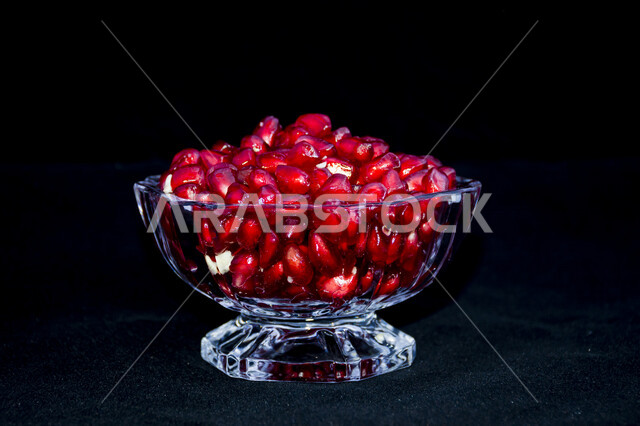 صورة مقربة لصحن مليئ بحبات الرمان الطازج اللذيذ ، فاكهة الرمان الطازجة ، وعاء مليئ بحبوب الرمان اللذيذ مصورة على خلفية سوداء ، بذور الرمان 