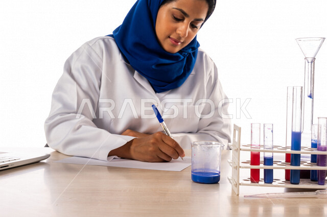 طبيبة مختبرات طبيه عربيه سعوديه خليجيه ترتدي معطف أبيض، إجراء التفاعلات الكيميائيه  داخل المختبر، تجارب و أبحاث طبيه، تسجيل النتائج و الملاحظات, دراسات وتحاليل, مواد كيميائيه