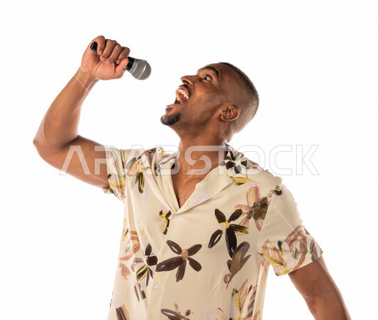 بورتريه لشاب اسمر عربي خليجي سعودي يمسك المايكروفون، تقديم العروضات المسرحية، القاء الخطابات، الحوارات والنقاشات، اداء تمثيلي، الفن المسرحي الغنائي، ملابس كاجوال، بشرة سمراء، خلفية بيضاء