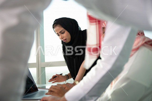 فريق عمل سعودي خليجي باجتماع اونلاين مع العميل باستخدام الكمبيوتر المحمول ، تسجيل ملاحظات على دفتر الملاحظات ، شركاء عمل