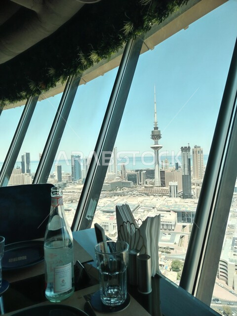 إطلالة من داخل أحد المباني على برج التحرير للاتصالات السلكية واللاسلكية في النهار، الأبراج وناطحات السحاب في مدينة الكويت، معلم سياحي مشهور، التصميم الهندسي المعماري المميز والواجهة الحضارية في دولة الكويت، التقدم العمراني للمنشأت السكنية والتجارية