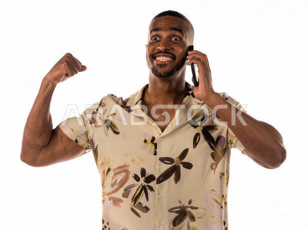 Portrait of a young Saudi Arabian Gulf Arab man making a call through a mobile phone, facial and hand gestures indicating strength, wearing casual clothes, brown skin, white background
