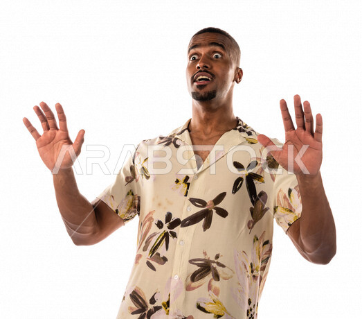 Portrait of a Saudi Arabian Gulf young man, facial and hands gestures that indicate amazement and astonishment, a brown young man, brown skin, wearing casual clothes, white background