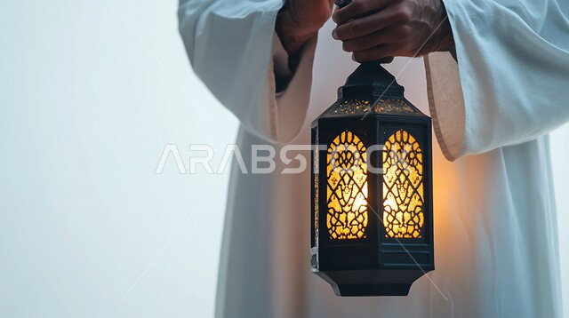 إضاءة وزينة رمضان المبارك, بورتريه مقرب لايدي رجل يحمل فانوس معدني تقليدي مزخرف مضيء, أنوار و ديكورات في الأجواء الرمضانية الروحانية ,تحف و فوانيس اسلامية للاحتفال بقدوم شهر الخير، خلفية بيضاء