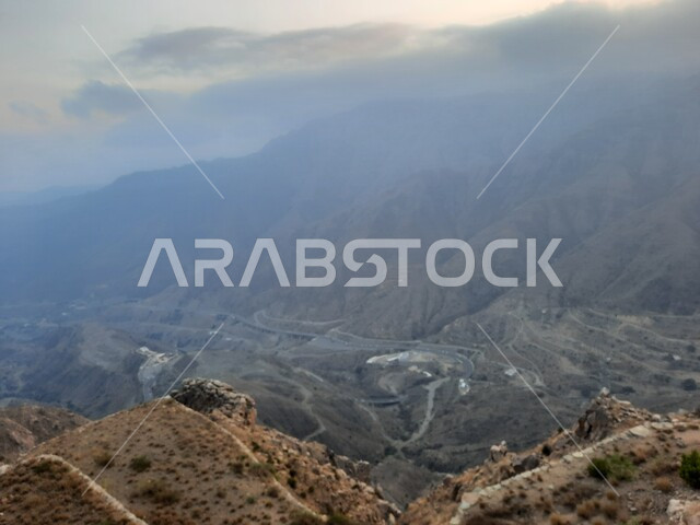 التضاريس على سفوح الجبل، سلاسل الجبال الصخرية، البيئة الجبلية لمنطقة أبها في عسير، أماكن طبيعية للمغامرات ورحلات السفاري، السحب والغيوم الكثيفة على القمم والمرتفعات والجبال العالية