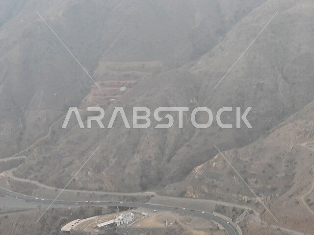 المرتفعات والقمم والبيئة الجبلية والطبيعة في المملكة العربية السعودية، طريق اسفلتي ملتوي وعر وسط الجبال الصخرية في منطقة أبها في عسير، حركة مرور وسير السيارات على الجبال، السحب والغيوم الكثيفة التي تغطي سفوح الجبل