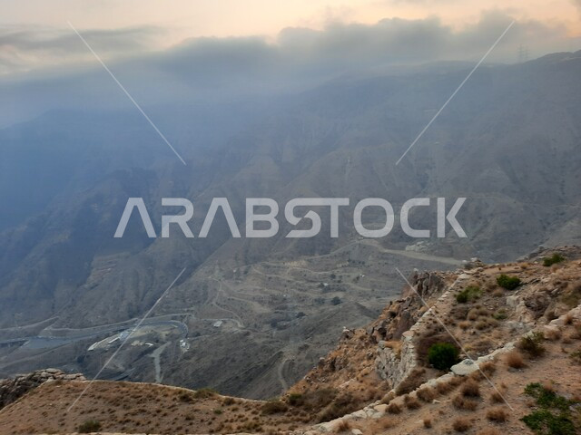 Thick clouds covering the mountain slopes, natural areas for adventures and safaris, peaks, heights and nature in the Kingdom of Saudi Arabia, a distinctive elevated view of the mountainous environment of the Abha region in Asir