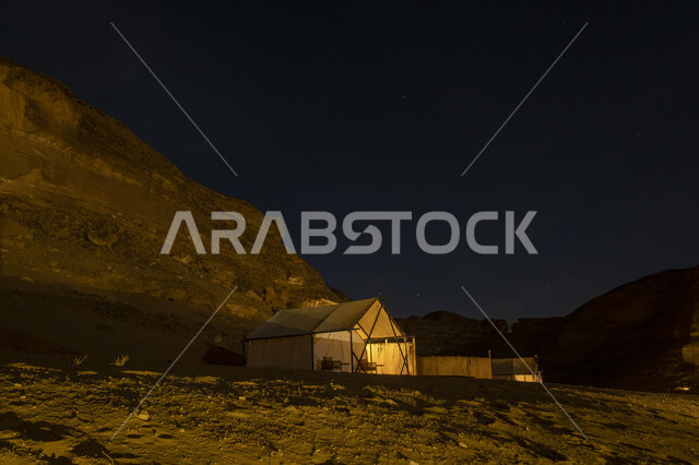 التكوينات والتشكيلات الصخرية في الصحاري، خيمة بيضاء في صحراء المملكة العربية السعودية في الليل، مغامرة ورحلة ترفيهية، التخييم في المناطق الصحراوية في محافظة العلا، جلسة وكشتة شبابية في البرية، مكان ومنطقة سياحية مشهورة