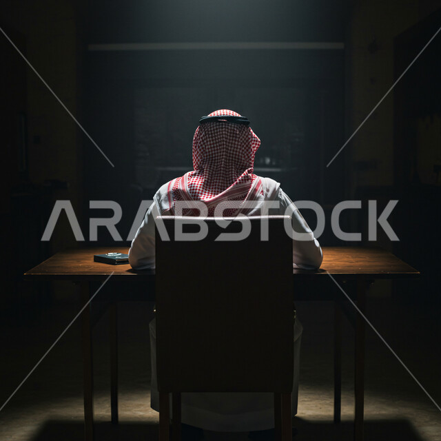 العمل في مكاتب وشركات المملكة العربية السعودية، إنجاز المهام المطلوبة، متابعة الأعمال بجد واجتهاد، صورة من الخلف لرجل عربي خليجي سعودي يرتدي الثوب التقليدي والشماغ يجلس خلف طاولة المكتب 