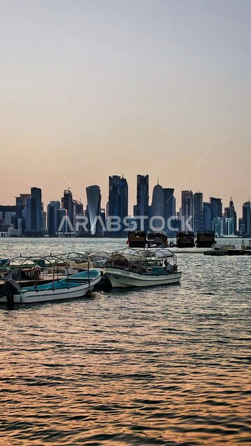 الواجهة البحرية في دولة قطر، إطلالة الأبراج وناطحات السحاب على البحر، أفق مدينة الدوحة مع القوارب الخشبية في مياه الخليج الهادئة عند شروق الشمس، الأماكن السياحية الساحلية المشهورة