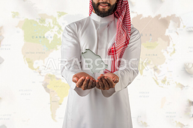 رجل عربي خليجي سعودي يحمل بيده خريطة المملكة العربية السعودية بتقنية الهولوجرام ، حب الوطن ، الاحتفال باليوم الوطني السعودي ، مجسم لخريطة المملكة السعودية ، جغرافيا وتضاريس السعودية ، مساحة السعودية الجغرافية