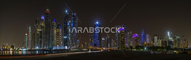 التقدم والتطور العمراني, مكان سياحي مشهور في الإمارات العربية المتحدة, جذب واستقطاب السياح من أنحاء العالم, صورة بانورامية للمباني والمنشآت المضيئة في الليل بمدينة دبي, الفن الهندسي المعماري لبناء الأبراج وناطحات السحاب على الطراز الحديث