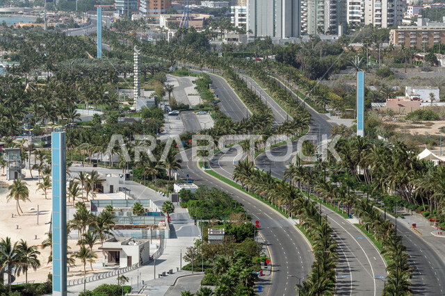 Urban growth and development in the Kingdom of Saudi Arabia, the architectural art of towers and skyscrapers in the city of Jeddah, trees and green plants surrounding public roads, interest in landscaping on the roads, traffic and cars in the streets