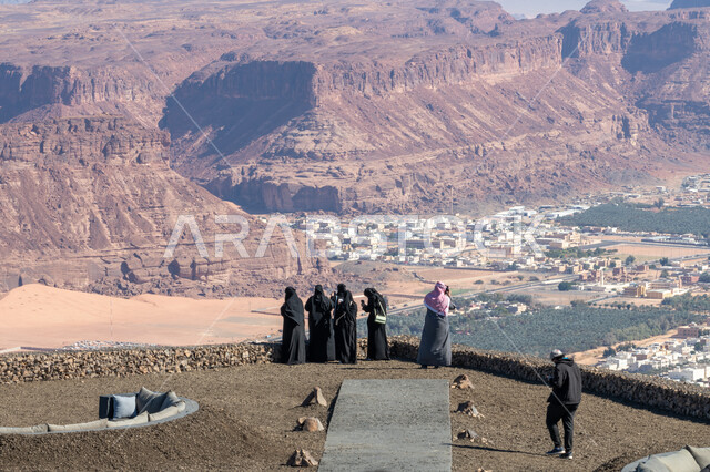 التكوينات والتشكيلات الصخرية الطبيعية بالمملكة العربية السعودية، القمم والمرتفعات الجبلية، أماكن سياحية لجذب واستقطاب السياح، صورة من لمجموعة من السياح العربيين الخليجيين السعوديين يرتدون الملابس التقليدية يقفون أمام المعالم التاريخية الأثرية في مدينة العلا