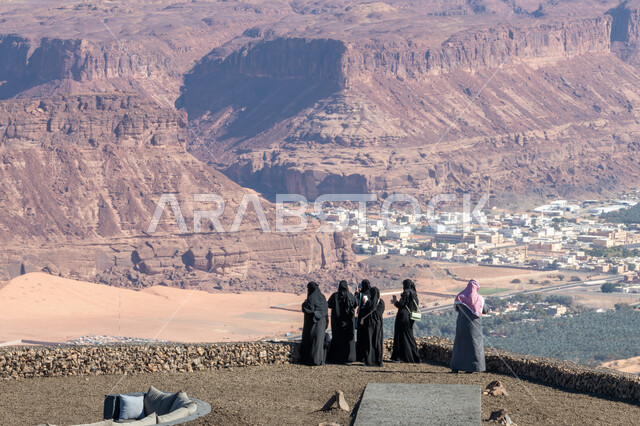 المعالم التاريخية الأثرية في مدينة العلا بالمملكة العربية السعودية، القمم والمرتفعات الجبلية، أماكن سياحية لجذب واستقطاب السياح، صورة من لمجموعة من السياح العربيين الخليجيين السعوديين يرتدون الملابس التقليدية يقفون أمام التكوينات والتشكيلات الصخرية الطبيعية 