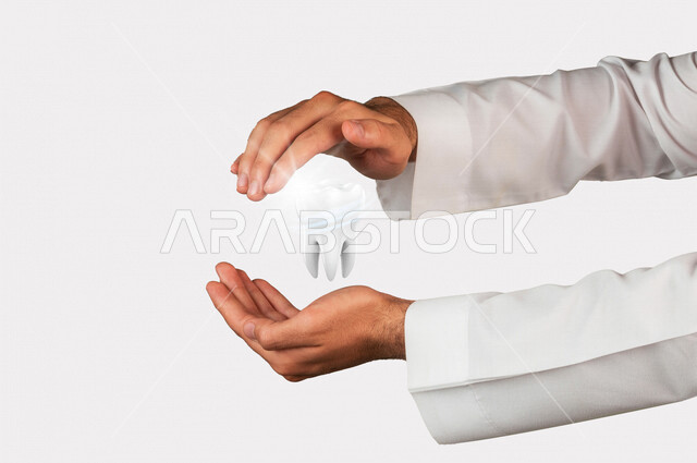 صورة مقرّبة لرجل عربي سعودي خليجي يحمل بين يديه مجسم هولوجرامي لضرس ، طب و صحة الأسنان ، حماية الأسنان وعلاج التسوس.