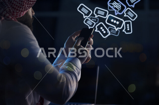 صورة مقربة من الخلف لرجل عربي خليجي سعودي بين يديه هاتف محمول ، خروج فقاعات التفكير متطايرة خاصة بتقنية ثلاثية الأبعاد ، الدردشة و التواصل عبر التطبيقات مواقع التواصل الإجتماعي