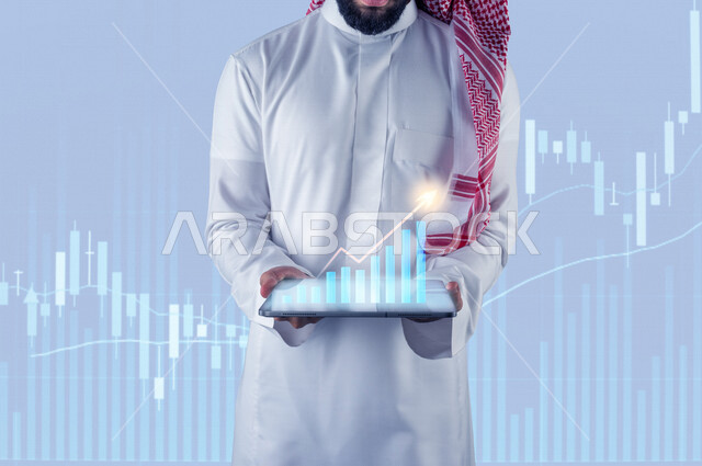 صورة مقربة لرجل عربي سعودي خليجي يحمل بيديه جهاز تقني ذكي عليه رسومات بيانية ثلاثية الأبعاد بتقنية الهولوجرام ، صعود و نزول البورصة المالية ، الاستثمار المالي و الاقتصادي ، التطور الإقتصادي