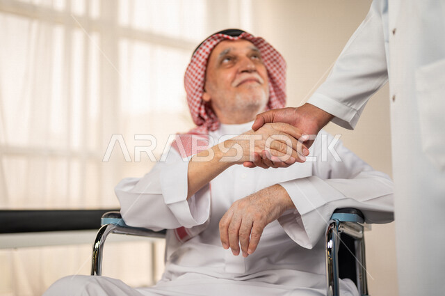 تقديم أفضل الخدمات الصحية لمرضى كبار السن في المستشفى , مريض مسن عربي سعودي خليجي يجلس على كرسي متحرك , يقوم بشكر وتقدير الطبيب لجهوده ورعايته الطبية , مفهوم الطب والرعاية الصحية .