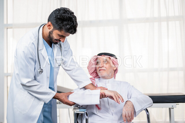 مريض عربي سعودي كبير بالسن يشكو من آلام في الكتف واليد , يقوم الطبيب بفحص المريض والتأكد من سلامة اليد , صحة وأطباء , حالة مرضية , مهن ووظائف طبية , خلفية بيضاء .
