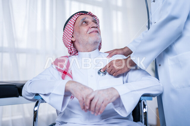 طبيب باطنية عربي سعودي خليجي يقوم بتقديم الرعاية الصحية المناسبة لمريض كبير بالسن في المستشفى , يقوم الطبيب بسماع دقات قلب المريض للتأكد من سلامة المريض , مفهوم الطب والرعاية الصحية .
