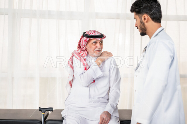 مريض عربي سعودي كبير بالسن يشكو من آلام في الكتف واليد , يقوم الطبيب بفحص المريض والتأكد من سلامة اليد , صحة وأطباء , حالة مرضية , مهن ووظائف طبية , خلفية بيضاء .