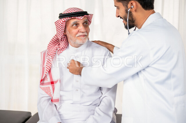 طبيب باطنية عربي سعودي خليجي يقوم بتقديم الرعاية الصحية المناسبة لمريض كبير بالسن في المستشفى , يقوم الطبيب بسماع دقات قلب المريض للتأكد من سلامة المريض , مفهوم الطب والرعاية الصحية .