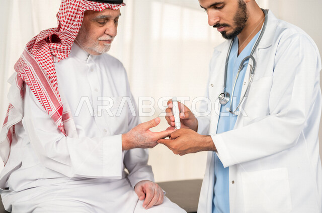 طبيب سعودي خليجي يقوم بفحص مريض كبير بالسن يعاني من داء السكري ، مشاكل ارتفاع وانخفاض السكر في الدم ، جهاز قياس السكر في الدم خاص لمرضى السكري  ، حالة مرضية .
