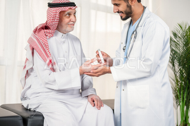طبيب سعودي خليجي يقوم بفحص مريض كبير بالسن يعاني من داء السكري ، مشاكل ارتفاع وانخفاض السكر في الدم ، جهاز قياس السكر في الدم خاص لمرضى السكري  ، حالة مرضية .