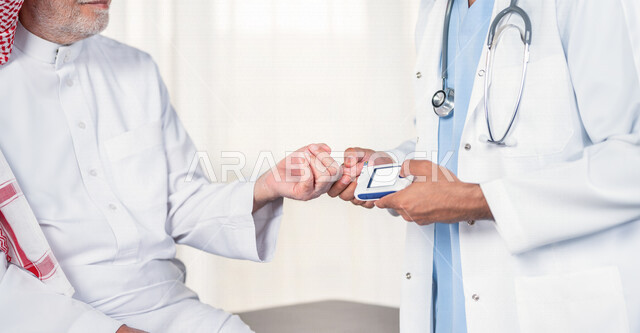 طبيب سعودي خليجي يقوم بفحص مريض كبير بالسن يعاني من داء السكري ، مشاكل ارتفاع وانخفاض السكر في الدم ، جهاز قياس السكر في الدم خاص لمرضى السكري  ، حالة مرضية .