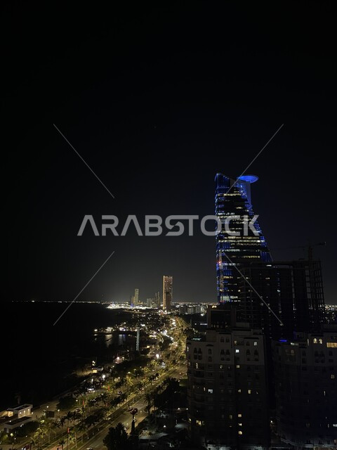 الواجهة البحرية لكورنيش مدينة جدة في المملكة العربية السعودية في الليل، الفن الهندسي المعماري للأبراج وناطحات السحاب المطلة على ساحل البحر الأحمر، التطور والتقدم العمراني للمباني والمنشآت السكنية والتجارية، مكان ومنطقة سياحية مشهورة
