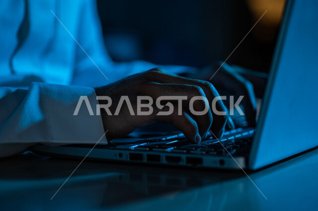 صورة مقربة ليد رجل عربي خليجي سعودي يستخدم الحاسوب المحمول ،الكتابة من خلال لوحة المفاتيح ، ادخال البيانات، صناعة المحتويات النصية،التسويق والترويج للمواقع الالكترونية، القيام بالاعمال الادارية ،التعليم الالكتروني