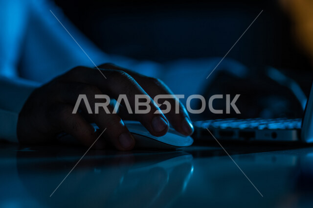 صورة مقربة ليد رجل عربي خليجي سعودي يستخدم الحاسوب المحمول ،يستخدم الفأرة والكتابة من خلال لوحة المفاتيح ، ادخال البيانات، صناعة المحتويات النصية ،التسويق والترويج للمواقع الالكترونية، القيام بالاعمال الادارية ،التعليم الالكتروني