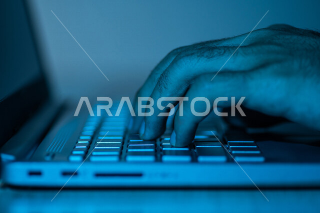 صورة مقربة ليد رجل عربي خليجي سعودي يستخدم الحاسوب المحمول ،الكتابة من خلال لوحة المفاتيح ، ادخال البيانات، صناعة المحتويات النصية،التسويق والترويج للمواقع الالكترونية، القيام بالاعمال الادارية ،التعليم الالكتروني