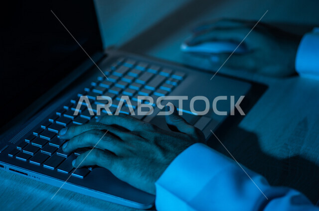 صورة مقربة ليد رجل عربي خليجي سعودي يستخدم الحاسوب المحمول ،يستخدم الفأرة والكتابة من خلال لوحة المفاتيح ، ادخال البيانات، صناعة المحتويات النصية ،التسويق والترويج للمواقع الالكترونية، القيام بالاعمال الادارية ،التعليم الالكتروني