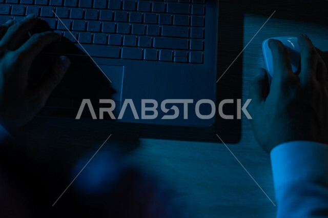 صورة مقربة ليد رجل عربي خليجي سعودي يستخدم الحاسوب المحمول ،يستخدم الفأرة والكتابة من خلال لوحة المفاتيح ، ادخال البيانات، صناعة المحتويات النصية ،التسويق والترويج للمواقع الالكترونية، القيام بالاعمال الادارية ،التعليم الالكتروني