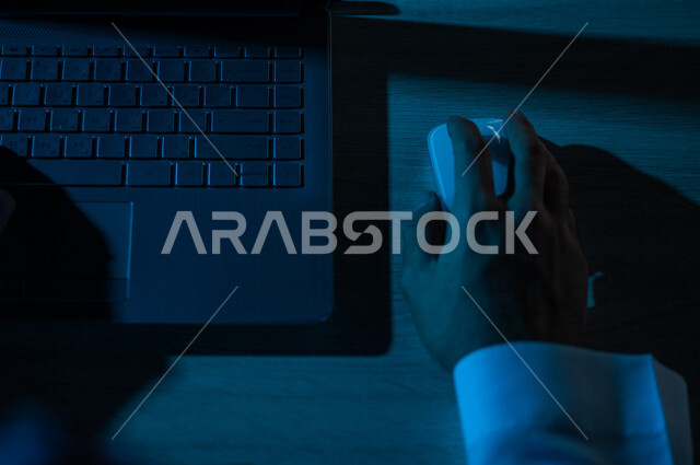 صورة مقربة ليد رجل عربي خليجي سعودي يستخدم الحاسوب المحمول ،يستخدم الفأرة والكتابة من خلال لوحة المفاتيح ، ادخال البيانات، صناعة المحتويات النصية ،التسويق والترويج للمواقع الالكترونية، القيام بالاعمال الادارية ،التعليم الالكتروني