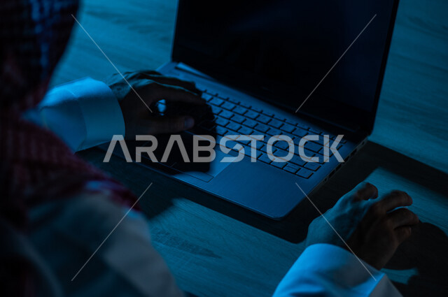 صورة مقربة ليد رجل عربي خليجي سعودي يستخدم الحاسوب المحمول ،يستخدم الفأرة والكتابة من خلال لوحة المفاتيح ، ادخال البيانات، صناعة المحتويات النصية ،التسويق والترويج للمواقع الالكترونية، القيام بالاعمال الادارية ،التعليم الالكتروني