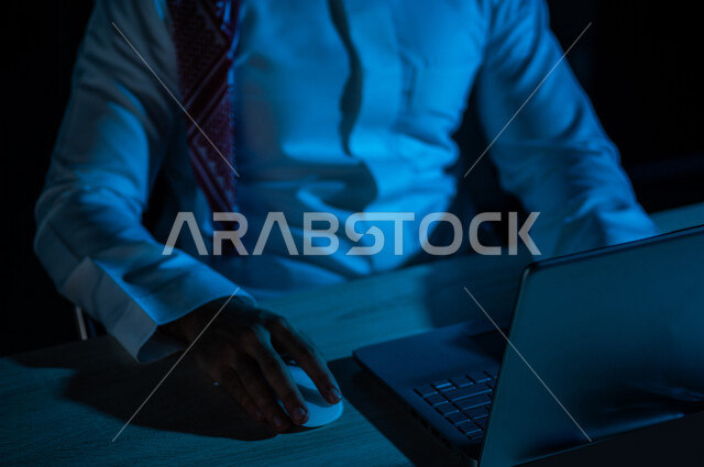 صورة مقربة ليد رجل عربي خليجي سعودي يستخدم الحاسوب المحمول ،يستخدم الفأرة والكتابة من خلال لوحة المفاتيح ، ادخال البيانات، صناعة المحتويات النصية ،التسويق والترويج للمواقع الالكترونية، القيام بالاعمال الادارية ،التعليم الالكتروني
