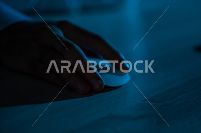 صورة مقربة ليد رجل عربي خليجي يستخدم الفارة الخاصة بالحاسوب المحمول ،وحدة ادخال في الحاسوب ، التاشير والنقر، التحكم بالالعاب ،انجاز اعمال الحاسوب