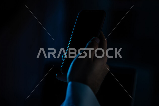 صورة مقربة ليد رجل عربي خليجي سعودي يستخدم الهاتف المحمول ، يقوم باتصال فيديو ،نقل البيانات والملفات بين الجهازين،  التسويق للتطبيقات الالكترونية ، التعليم الالكتروني، مشاهدة الافلام والفيديو