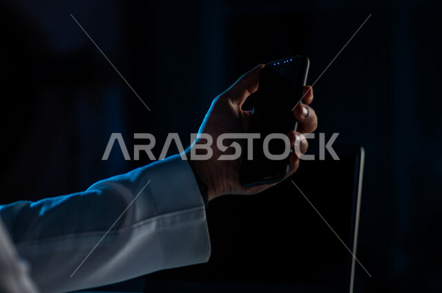 صورة مقربة ليد رجل عربي خليجي سعودي يستخدم الهاتف المحمول ، يقوم باتصال فيديو ،نقل البيانات والملفات بين الجهازين،  التسويق للتطبيقات الالكترونية ، التعليم الالكتروني، مشاهدة الافلام والفيديو