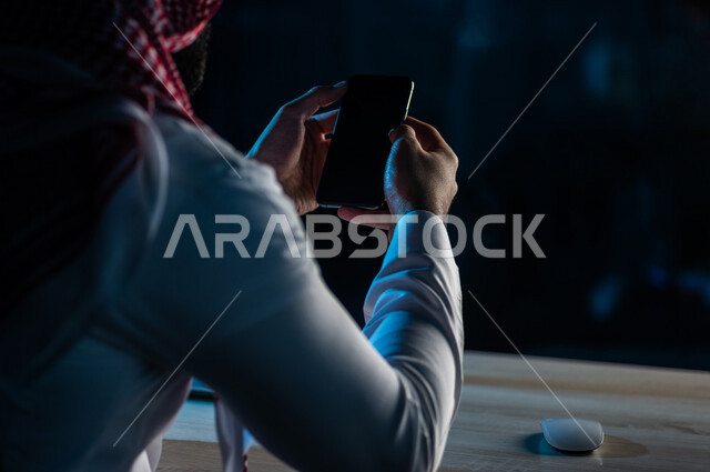 صورة مقربة ليد رجل عربي خليجي سعودي يستخدم الهاتف المحمول ، يقوم باتصال فيديو ،نقل البيانات والملفات بين الجهازين،  التسويق للتطبيقات الالكترونية ، التعليم الالكتروني، مشاهدة الافلام والفيديو