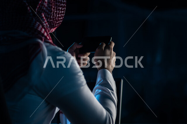 صورة مقربة ليد رجل عربي خليجي سعودي يستخدم الهاتف المحمول ، يقوم باتصال فيديو ،نقل البيانات والملفات بين الجهازين،  التسويق للتطبيقات الالكترونية ، التعليم الالكتروني، مشاهدة الافلام والفيديو