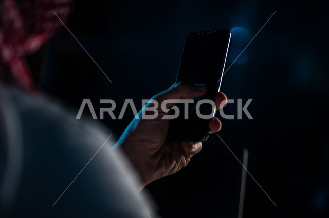 صورة مقربة ليد رجل عربي خليجي سعودي يستخدم الهاتف المحمول ، يقوم باتصال فيديو ،نقل البيانات والملفات بين الجهازين،  التسويق للتطبيقات الالكترونية ، التعليم الالكتروني، مشاهدة الافلام والفيديو