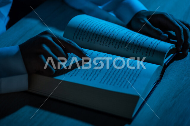 A close-up of a Saudi Arabian Gulf man reading a book, a scientific researcher, a university book, stories and novels, acquiring knowledge, education and culture