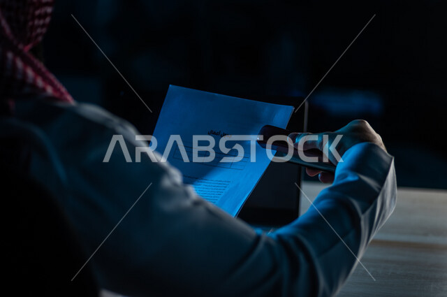 صورة مقربة لرجل عربي خليجي سعودي يحمل بيده اوراق خاصة بالعمل ،سكرتير يدير الاعمال الورقية ، تنظيم جدول الاعمال والمهام ، وثيقة التوظيف ، قراءة شروط عقد العمل ، الموافقة على العمل ، مفهوم التوظيف والعمل