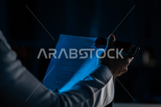 صورة مقربة لرجل عربي خليجي سعودي يحمل بيده اوراق خاصة بالعمل ،سكرتير يدير الاعمال الورقية ، تنظيم جدول الاعمال والمهام ، وثيقة التوظيف ، قراءة شروط عقد العمل ، الموافقة على العمل ، مفهوم التوظيف والعمل